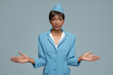 Wall Mural - Young african stewardess giving safety briefing. Blue background.