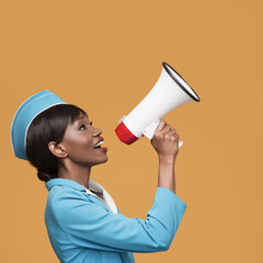 Wall Mural - Cheerful young african stewardess shouts into the loudspeaker. Orange background.