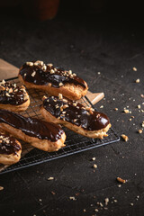 Chocolate eclairs filled with cream on dark background