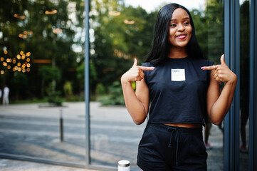 Fashionable feminist african american woman wear in black t-shirt and shorts, posed outdoor.