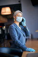 Wall Mural - Charming woman in medical mask talking on mobile phone