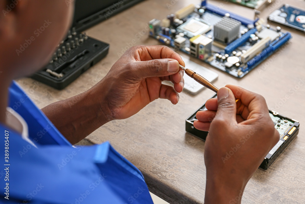 African-American technician repairing computer in service center
