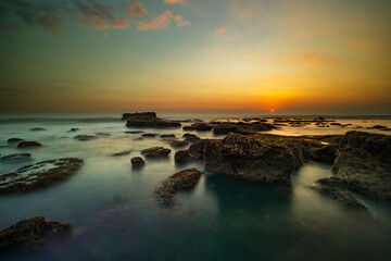 Wall Mural - Amazing seascape. Landscape background. Beach with rocks and stones. Low tide. Motion water. Slow shutter speed. Soft focus. Mengening beach, Bali, Indonesia