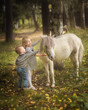Little blond girl and boy is standing near the little horse pony and hugging it