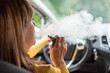 © thodonal - Woman smoking an e-cigarette in car