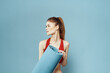 © SHOTPRIME STUDIO - athletic woman with fitness mat exercise slim figure red t-shirt blue background