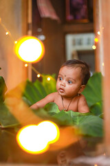 Canvas Print - Cute indian little child playing with green leaf and colorful light