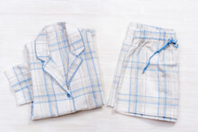 Folded Warm White Pajamas With Blue Checks Or Stripes On White Wood