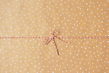 Bow From Christmas Red White Twine Cotton String Rope Cord On Brown Craft Paper With White Dots Gift Wrapping, Top View