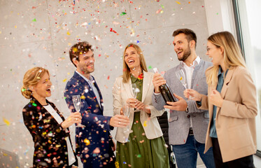 Wall Mural - Group of business people celebrating and toasting with confetti falling in the office