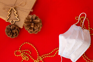 protection facial mask on red table surrounded by pine cones and new year christmas attributes