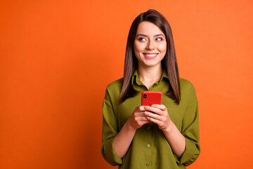 Wall Mural - photo of positive girl hold telephone look side empty space wear green shirt isolated orange color b