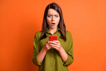 Wall Mural - photo of surprised upset girl hold smartphone open mouth wear green shirt isolated orange color back