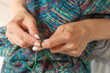 © mitsyko1971 - Close up of hands of unrecognizable woman knitting handmade clothes with spokes using  wool yarn. Concept of leisure activity.Knitting from yarn on  coarse spokes.