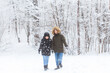 © satura_ - Young couple walking in a snowy park. Winter season.