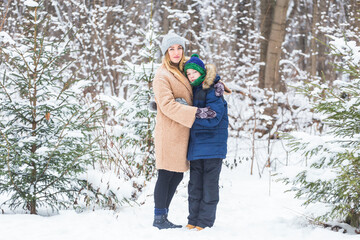 Portrait of happy mother with child son in winter outdoors. Snowy park. Single parent.