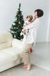 © satura_ - Happy young woman with lovely dog in living room with christmas tree. Holidays concept.