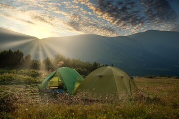 view of tourist tent in mountains at sunrise or sunset. Camping background. Adventure travel active lifestyle freedom concept. Summer vacation