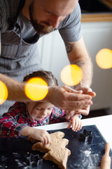 Hands of Father and daughter making cookies with tins on prepared dough. New year Christmas concept