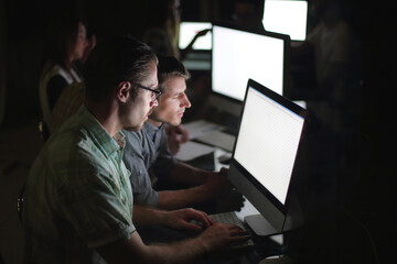 business team works on computers at night.
