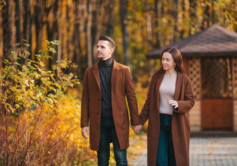 Happy family walking in autumn park on sunny fall day