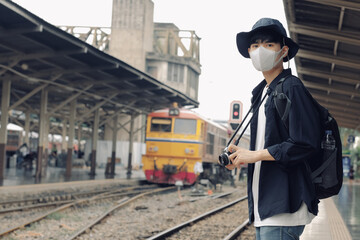 Wall Mural - Asian travelers men and camera in train station with medical face mask to protection the Covid-19, new normal lifestyle