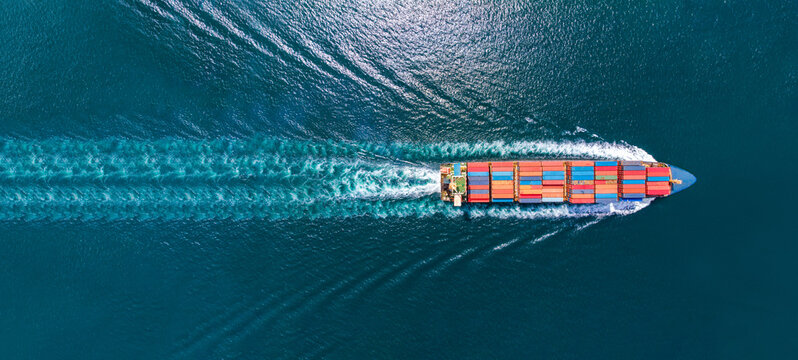 aerial top view of cargo ship with contrail in the ocean sea ship carrying container and running fro