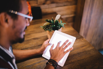 Crop ethnic man using tablet in creative workspace