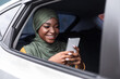 © Prostock-studio - Smiling Black Muslim Lady Using Smartphone While Riding Car On Backseat