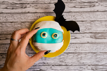 Decorated doughnut on Halloween, blue color with paper bats, a hand reaches out for food