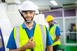 © winnievinzence - Portrait of confident male engineer foreman in safety helmet smile showing thumbs up in front of factory production. man operating machine at industrial plant. men at work concept.