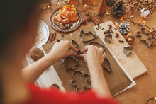 Person making Christmas gingerbread cookies, holiday advent. Hands cutting gingerbread dough