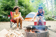 © Inti St. Clair - Sister roasting marshmallows over campfire in campground