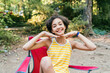 © Inti St. Clair - Happy teen girl sitting in camping chair in forest with big smile