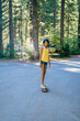 © Inti St. Clair - Portrait of smiling teen girl skateboarding on road in forest