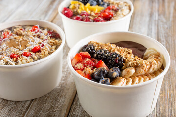A view of a three acai bowls on a wood surface.