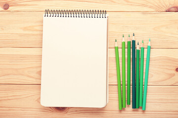 Wall Mural - Green pencils with notebook on brown wooden table