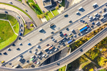 Aerial drone view of road interchange or highway intersection with busy urban traffic in modern city during sunny day. Traffic jam aerial view.