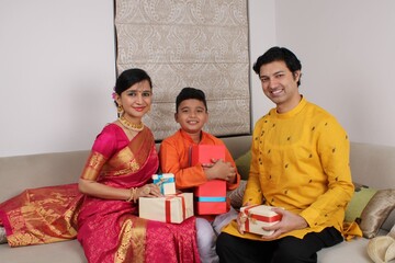 Smart Indian family of Four in ethnic wear holding Diwali Gifts.