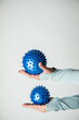Dwie niebieskie piłki do rehabilitacji trzymane na kobiecych rękach. 