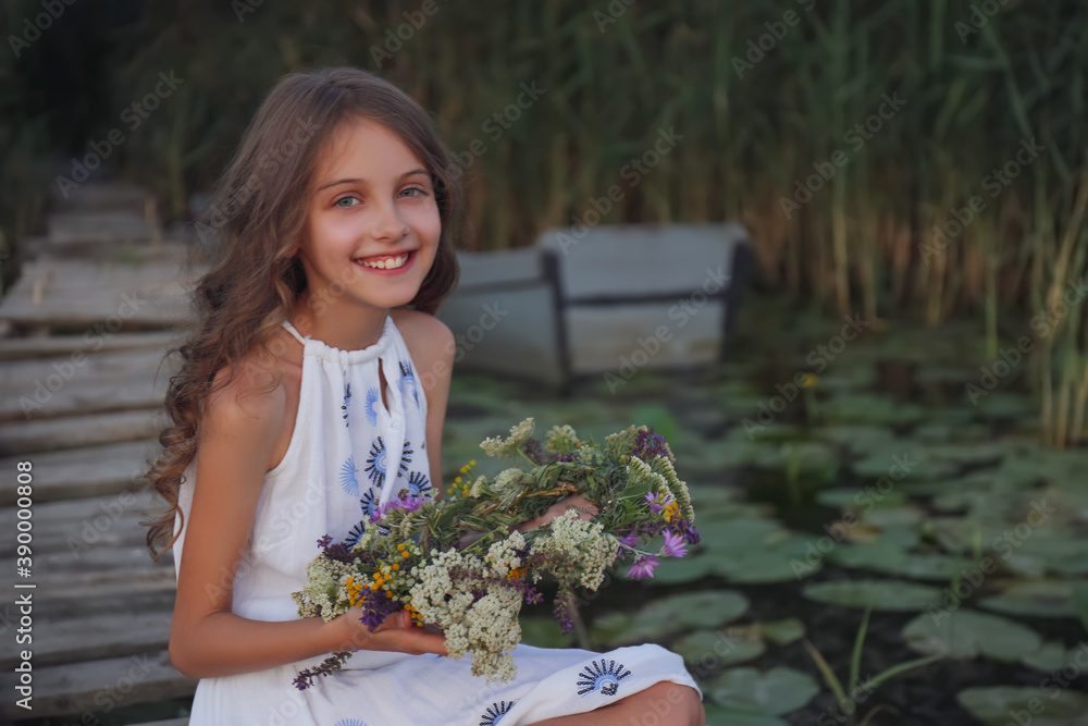 Cute little girl holding wreath made of beautiful flowers on pier near ...