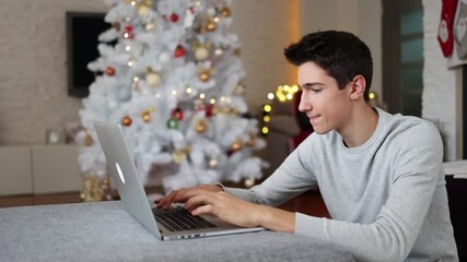 Wall Mural - Teenage boy using laptop at home in Christmas time
