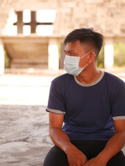 Handsome Indonesian young man wearing face mask in abandoned buildings. Portrait of confident Indonesian young man wearing face mask during coronavirus