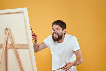 Wall Mural - Male artist stands in front of easel emotions drawing Creative approach yellow