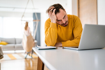 Frustrated young man working on laptop at home