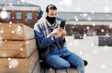 Poster - health, safety and pandemic concept - young woman wearing protective medical mask and using smartphone on city street over snow