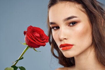 woman with a rose in her hands naked shoulders evening makeup red lips