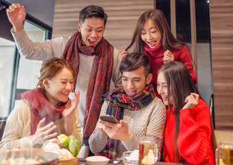 Wall Mural - excited friends celebrating good news watching smart phone in the restaurant