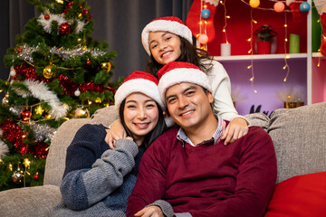 Portrait of happy family, father mother and daughter, celebrate Christmas in living room, holiday season