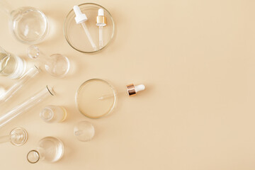 Wall Mural - Laboratory glassware and pipette with serum and oil on beige background. Natural medicine, cosmetic research, bio science, organic skin care products. Concept skincare. Dermatology.Flat lay, top view.